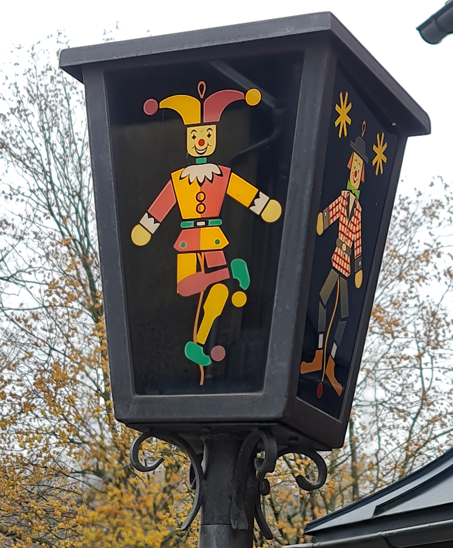 Laterne viereckig und dunkel mit bunten Bildern hier Harlekin und Clown - Straßenbeleuchtung in Seiffen Erzgebirge.