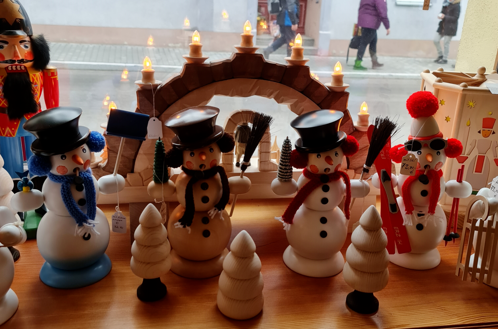 vier Räuchermännchen aus Holz in Form von einem Schneemann auf einer Fensterbank 3 haben schwarzen Zylinder auf dem Kopf einer eine Mütze mit roter Bommel und rotem Schal