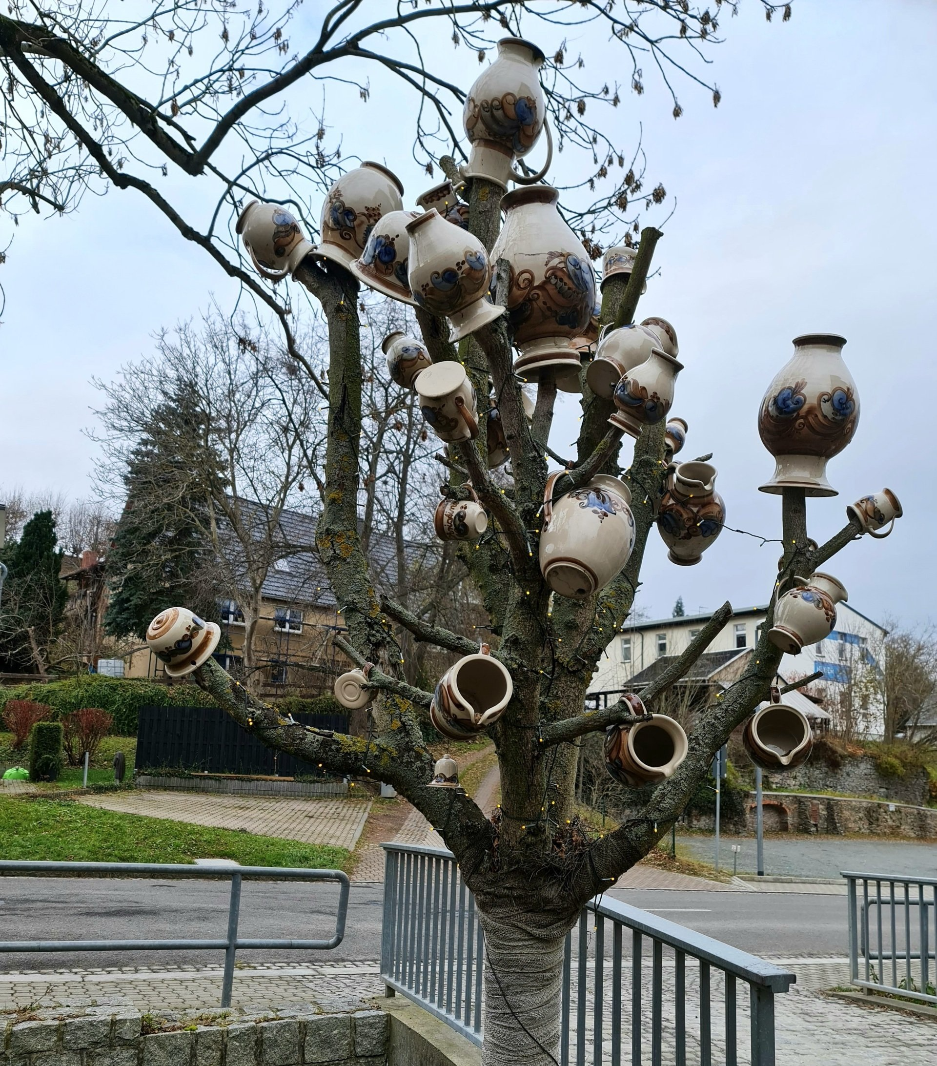 ein Baum ohne Blätter auf den Ästen sind verschiedene Keramik Töpfe aufgesteckt Heyde Keramik Jahnsdorf Erzgebirge