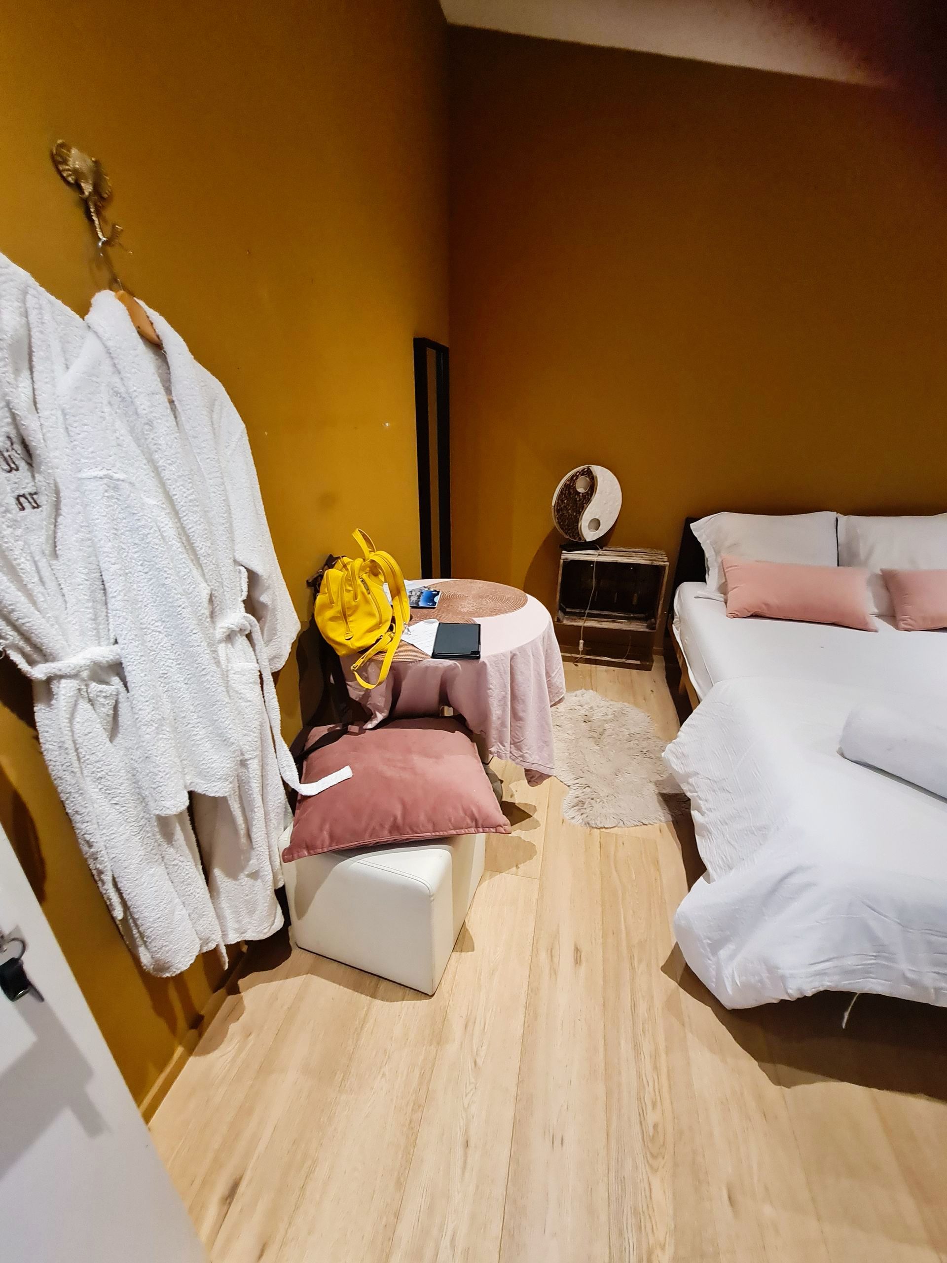 Blick in ein Zimmer mit Holzfussboden und braunen Wänden und weißem Bett