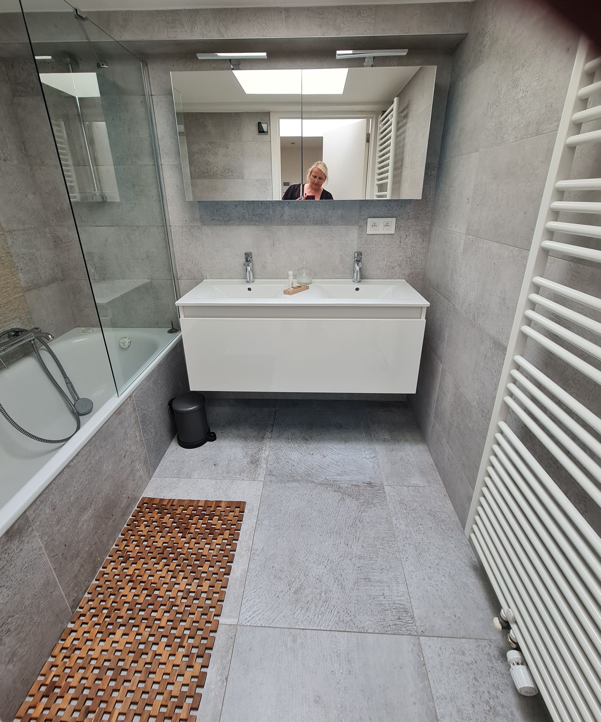 Badezimmer mit Wanne links und weißem Doppelwaschbecken und weissem Handtuchtrockner