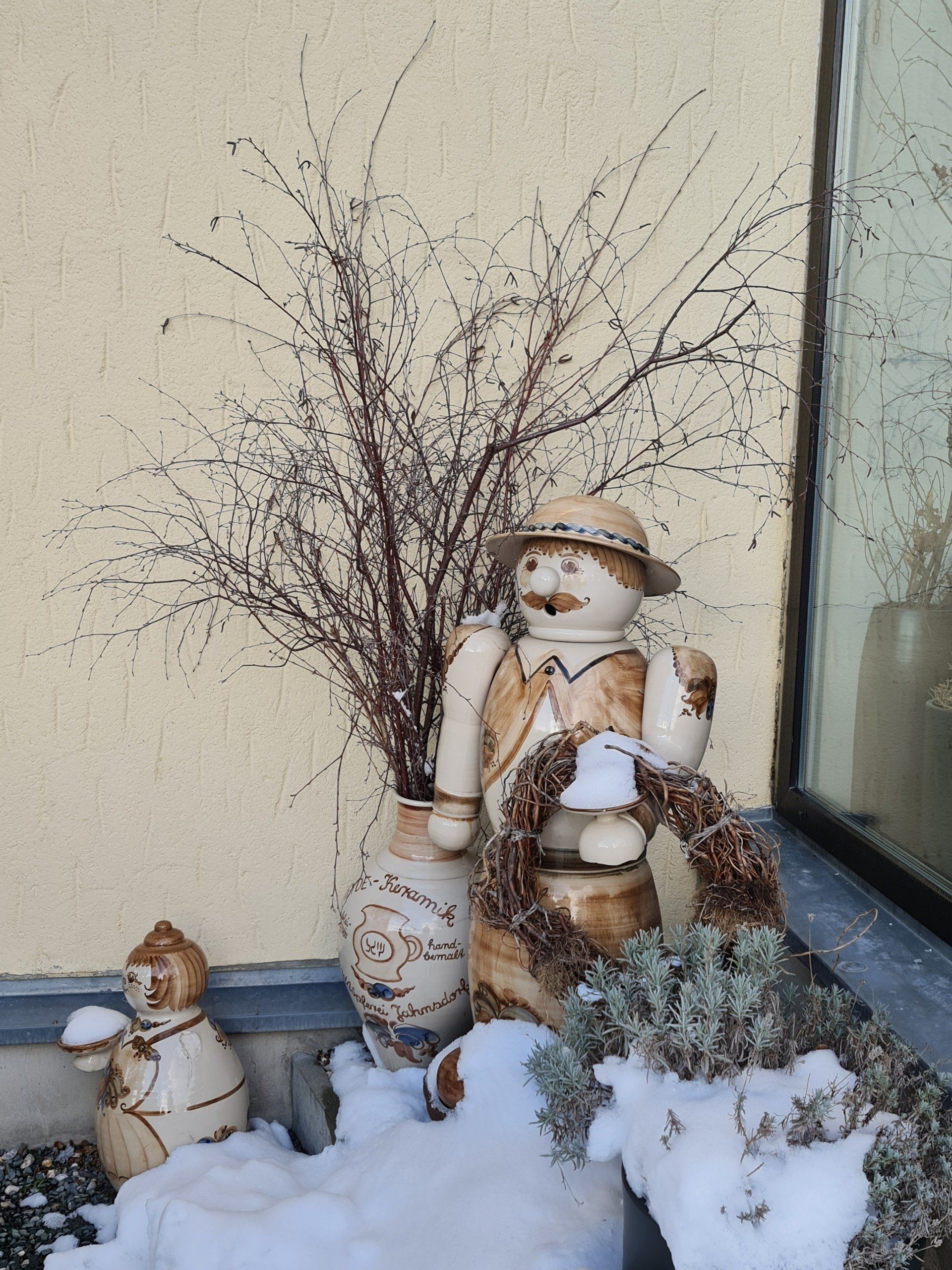 Keramik Räuchermann in beige und braun vor der Tür kleinere Figuren im Schnee