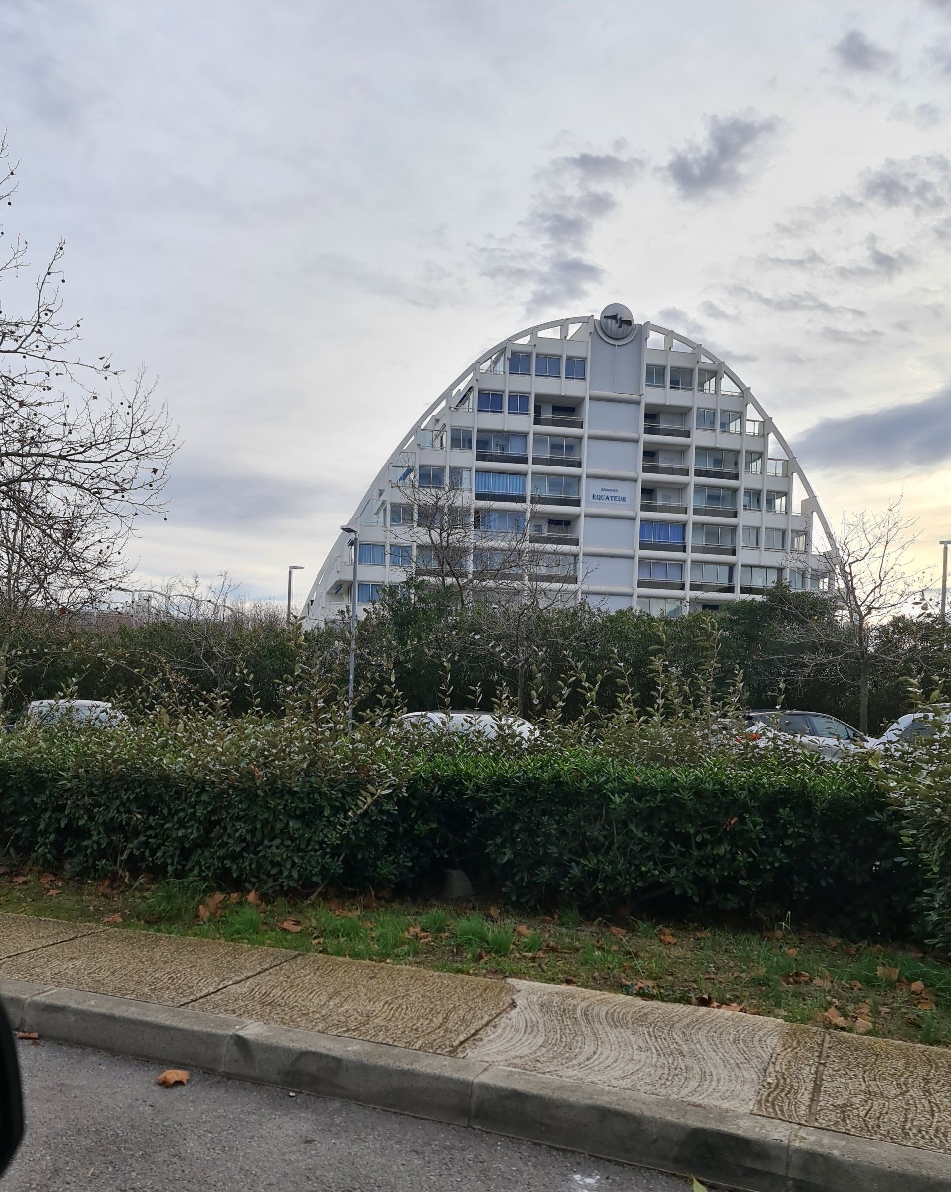 ein weißes großes Haus das nach oben halbrund gebaut ist und viele Balkone hat