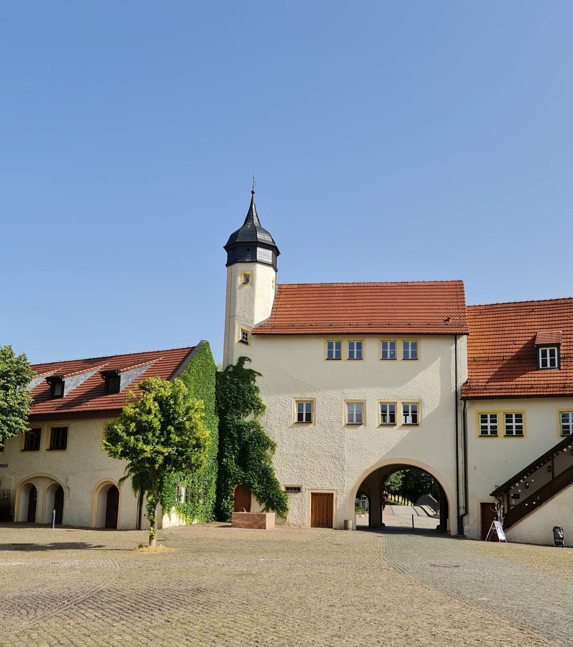 Blick auf zwei Gebäude eines Schlosses mit Turm und Torbogen