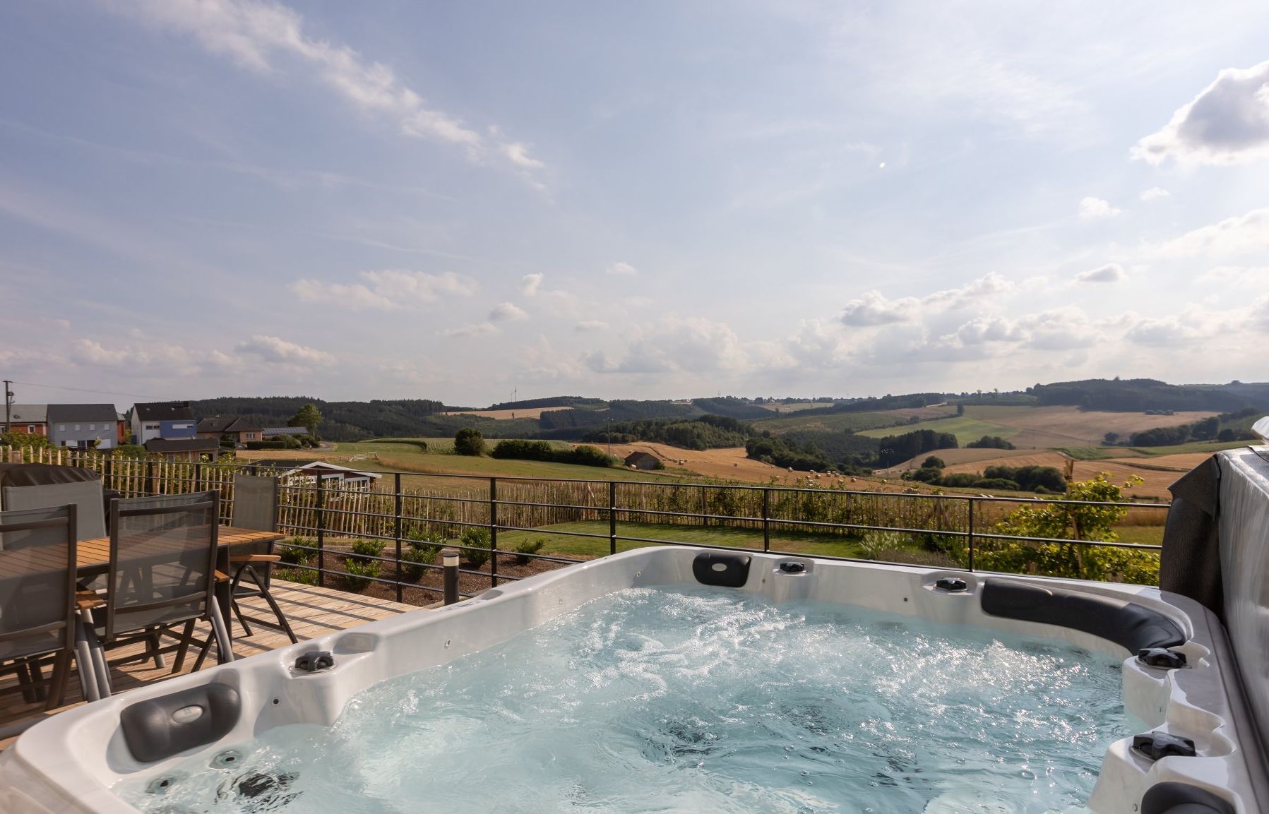 Aussicht von der Terrasse Whirlpool auf der Terrasse des Resort of Spirit mit traumhaftem Ausblick über grüne Felder und dichte Wälder – ein Ort für pure Entspannung inmitten der Natur.