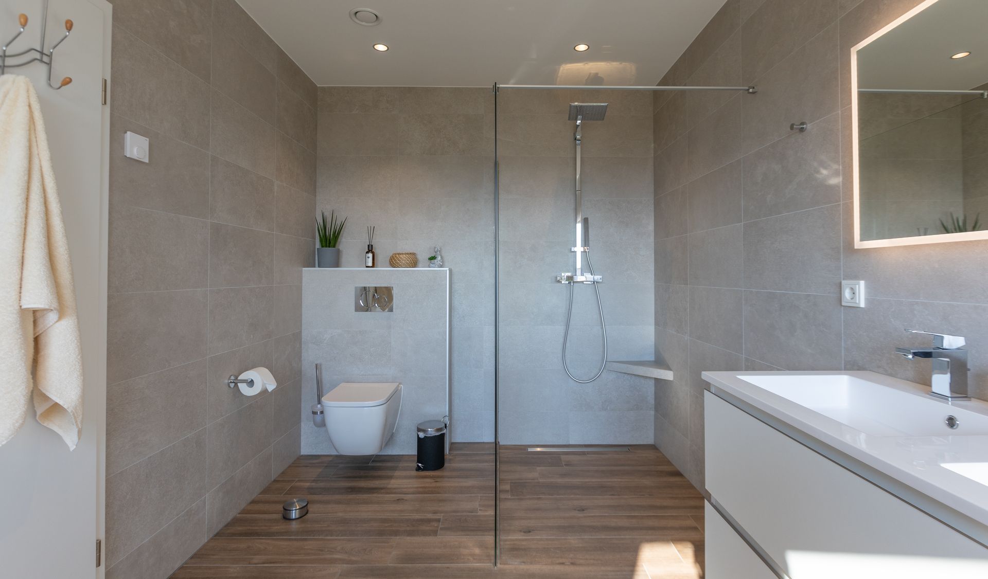 Links des Fotos ist die Toilette zu sehen. Eine Glaswand (italienische Wand) trennt diese von der Dusche ab, welche sowohl über eine Handbrause, als auch über eine Regenschauerfunktion verfügt.