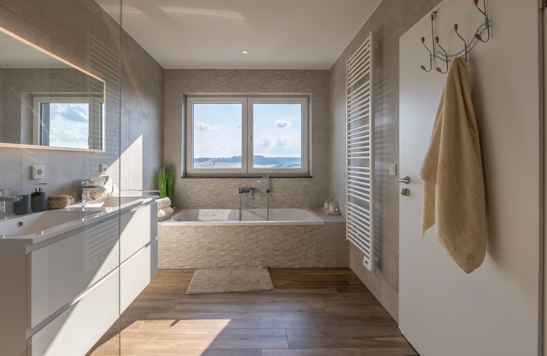 Die Badewanne befindet sich direkt unter dem nicht einsehbarem Fenster. Eine Handtuchheizung hängt direkt neben der Wanne.