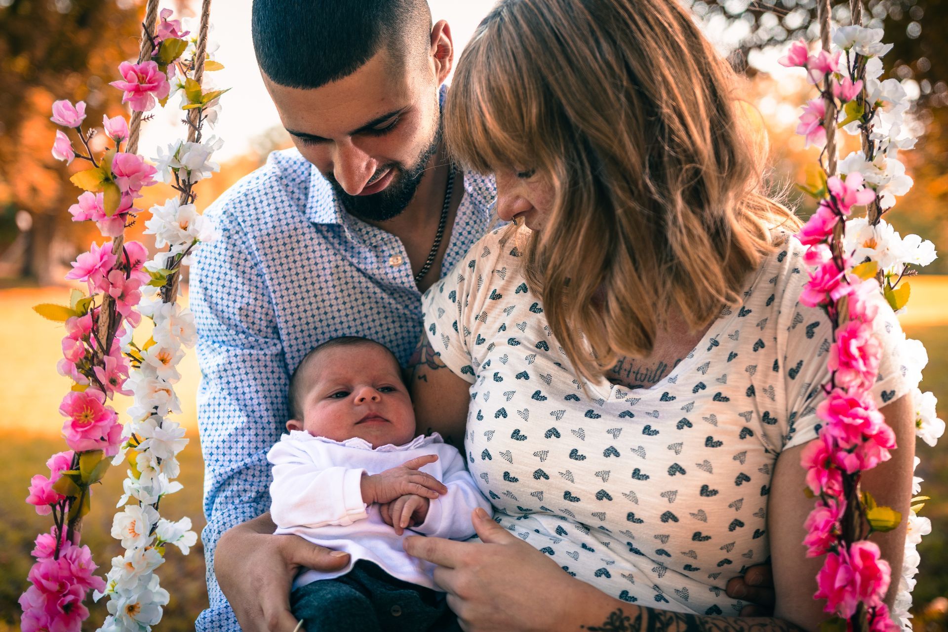 Emotionales Familienshooting mit Eltern und Neugeborenem auf einer dekorierten Schaukel