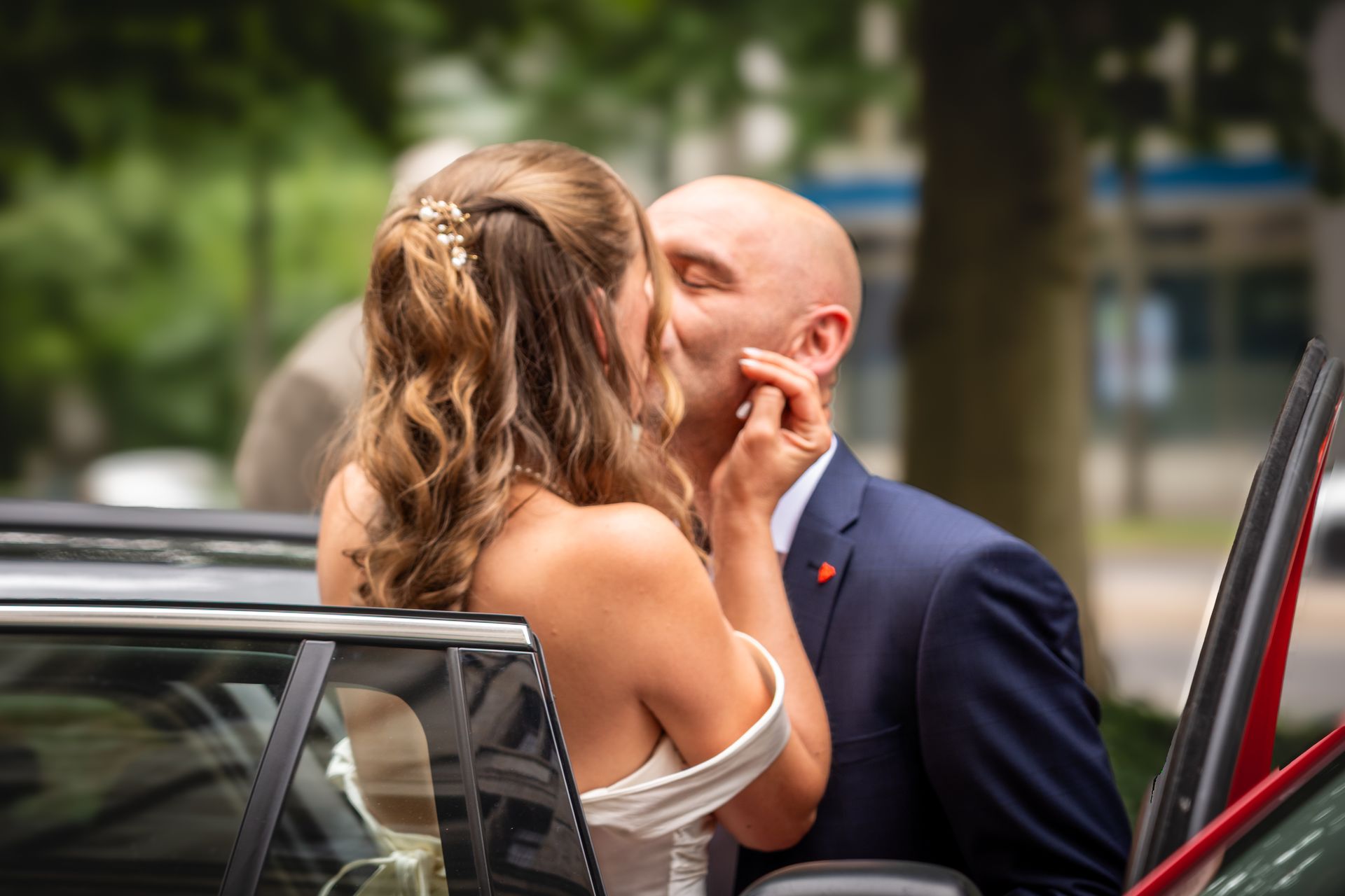 Emotionale Hochzeitsreportage mit Brautpaar beim Kuss am Hochzeitsauto im Grünen
