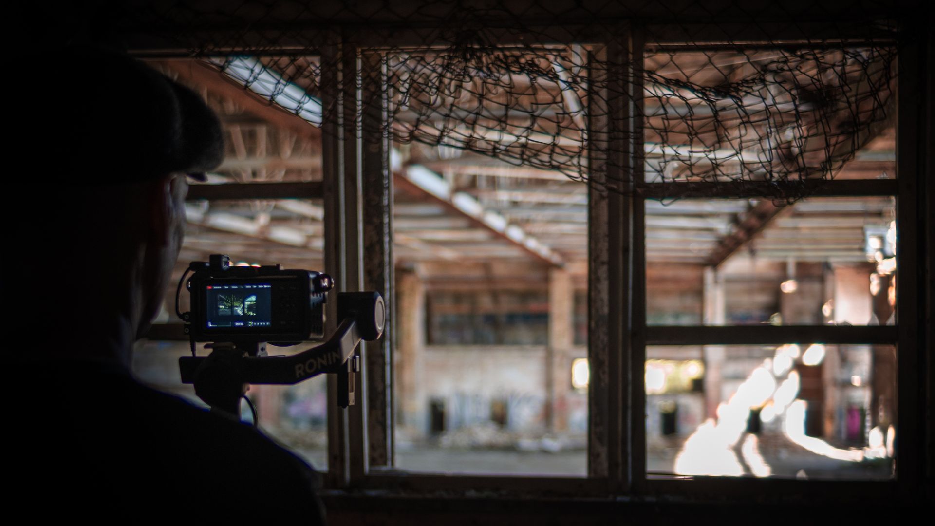 Fotograf filmt mit Kamera in einer verlassenen Industriehalle mit natürlichem Licht