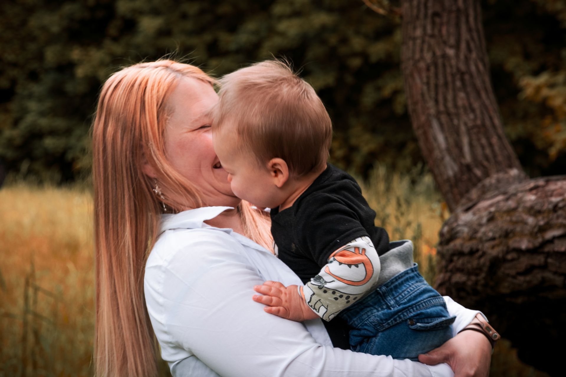 Emotionales Familienportrait einer Mutter mit Kleinkind in inniger Umarmung im Grünen