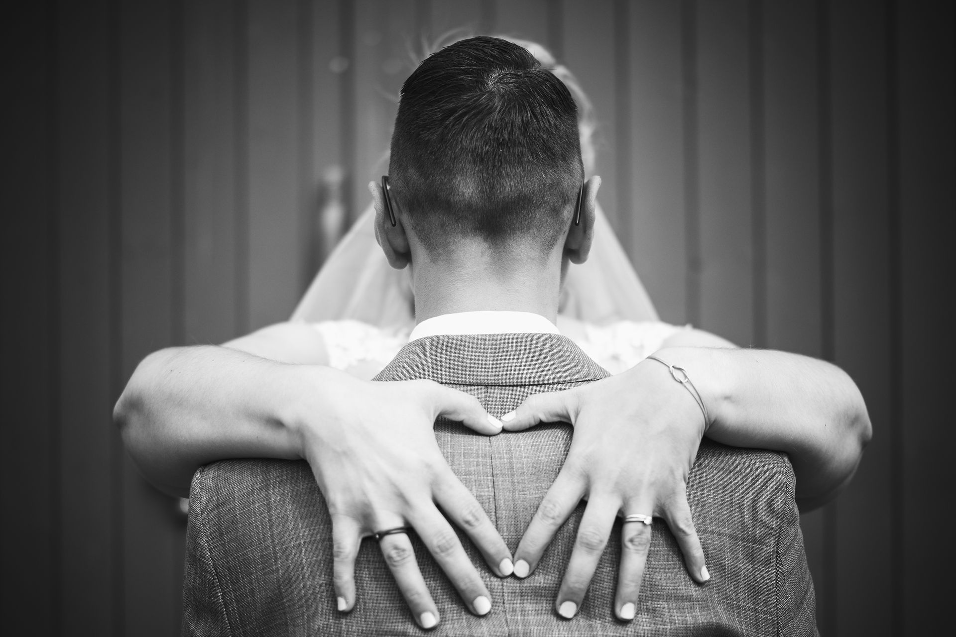 Braut formt mit ihren Händen ein Herz auf dem Rücken des Bräutigams – ein symbolträchtiger Moment während der Hochzeitsfeier auf dem Gelände des Kloster Nimbschen bei Grimma.