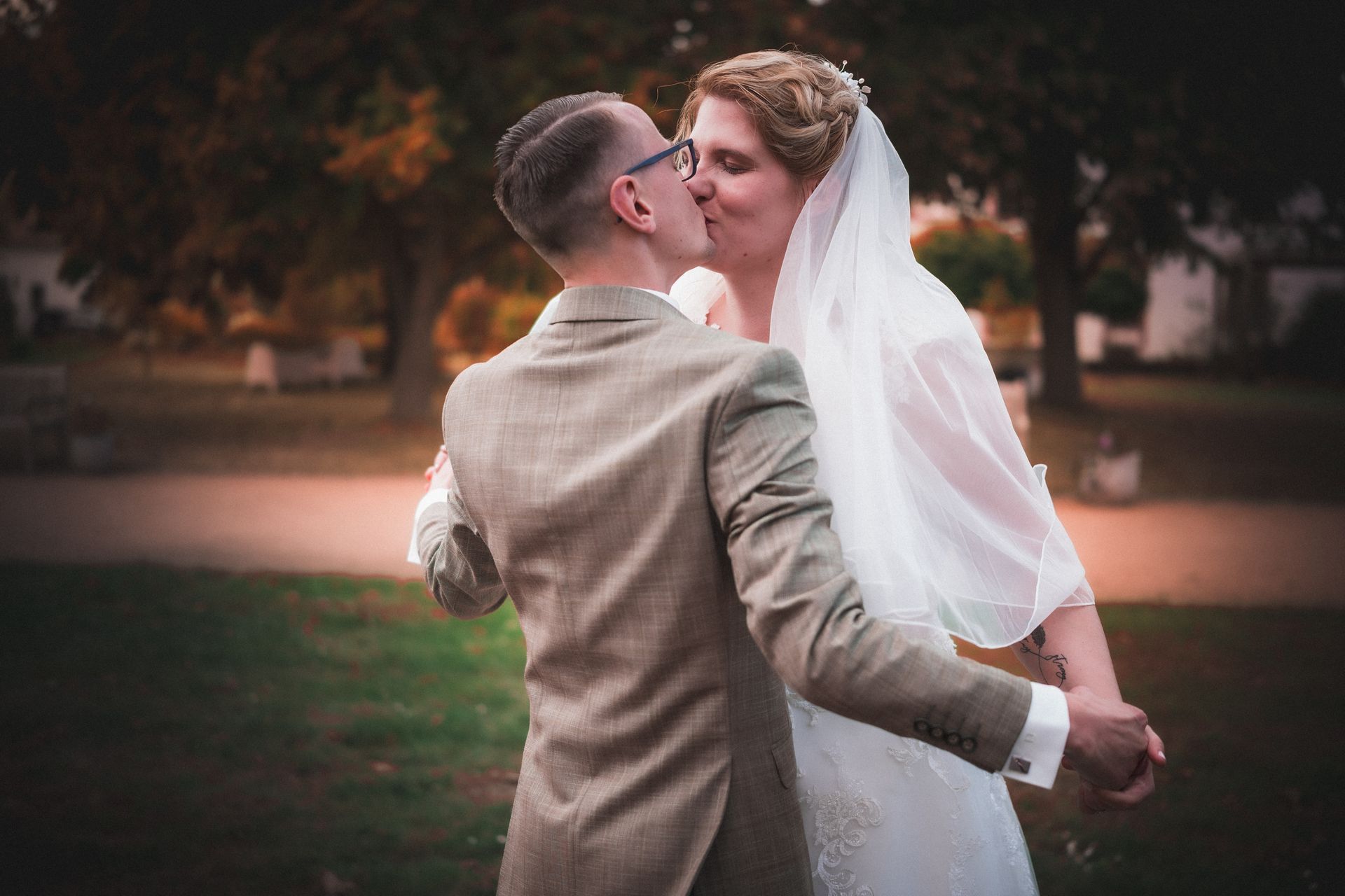 Braut und Bräutigam küssen sich beim Hochzeitstanz im Garten des Kloster Nimbschen bei Grimma. Der Moment zeigt Zuneigung und Nähe inmitten einer herbstlich warmen Atmosphäre.