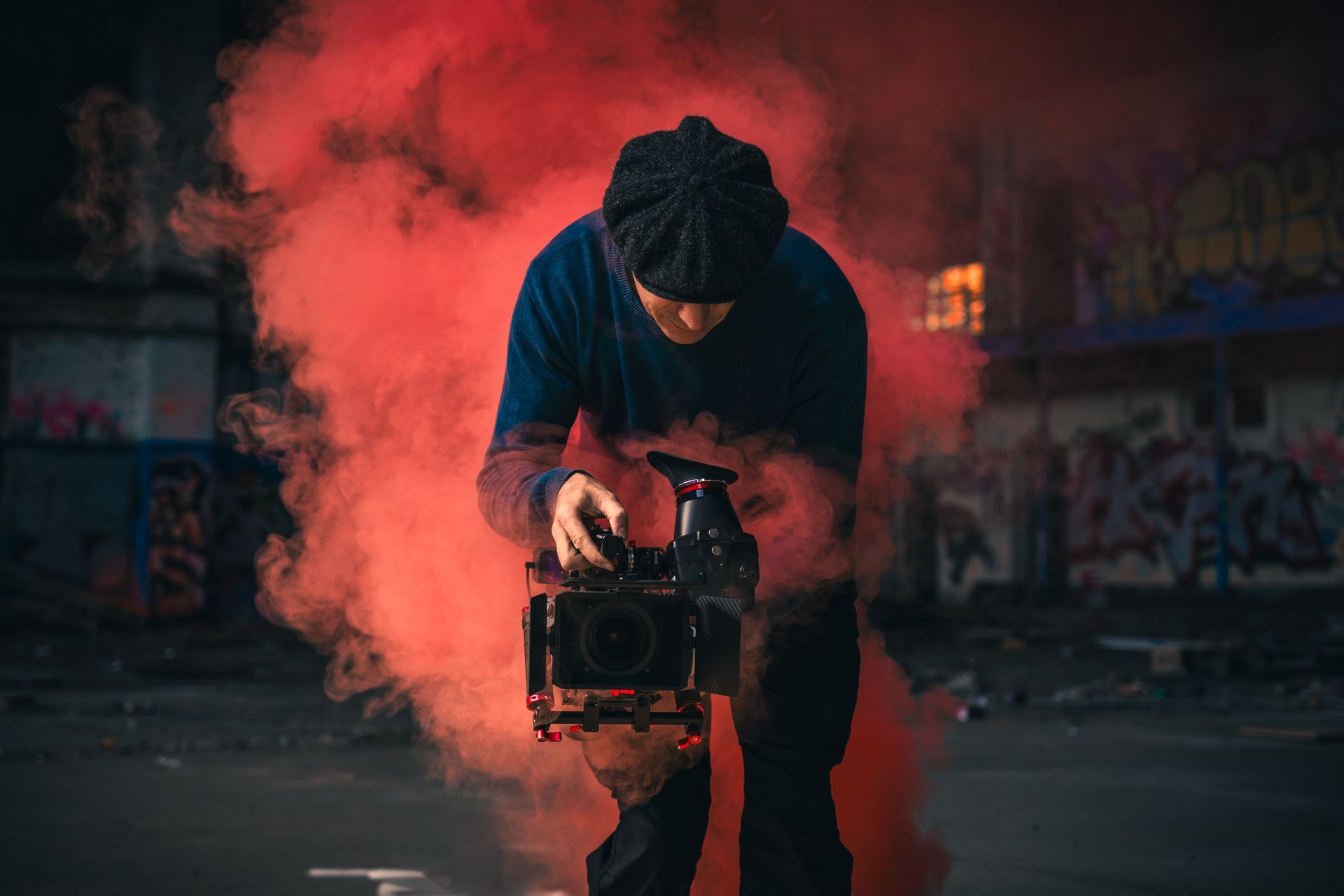 Künstlerisches Rauchportrait eines Filmemachers mit Kamera in rotem Rauch