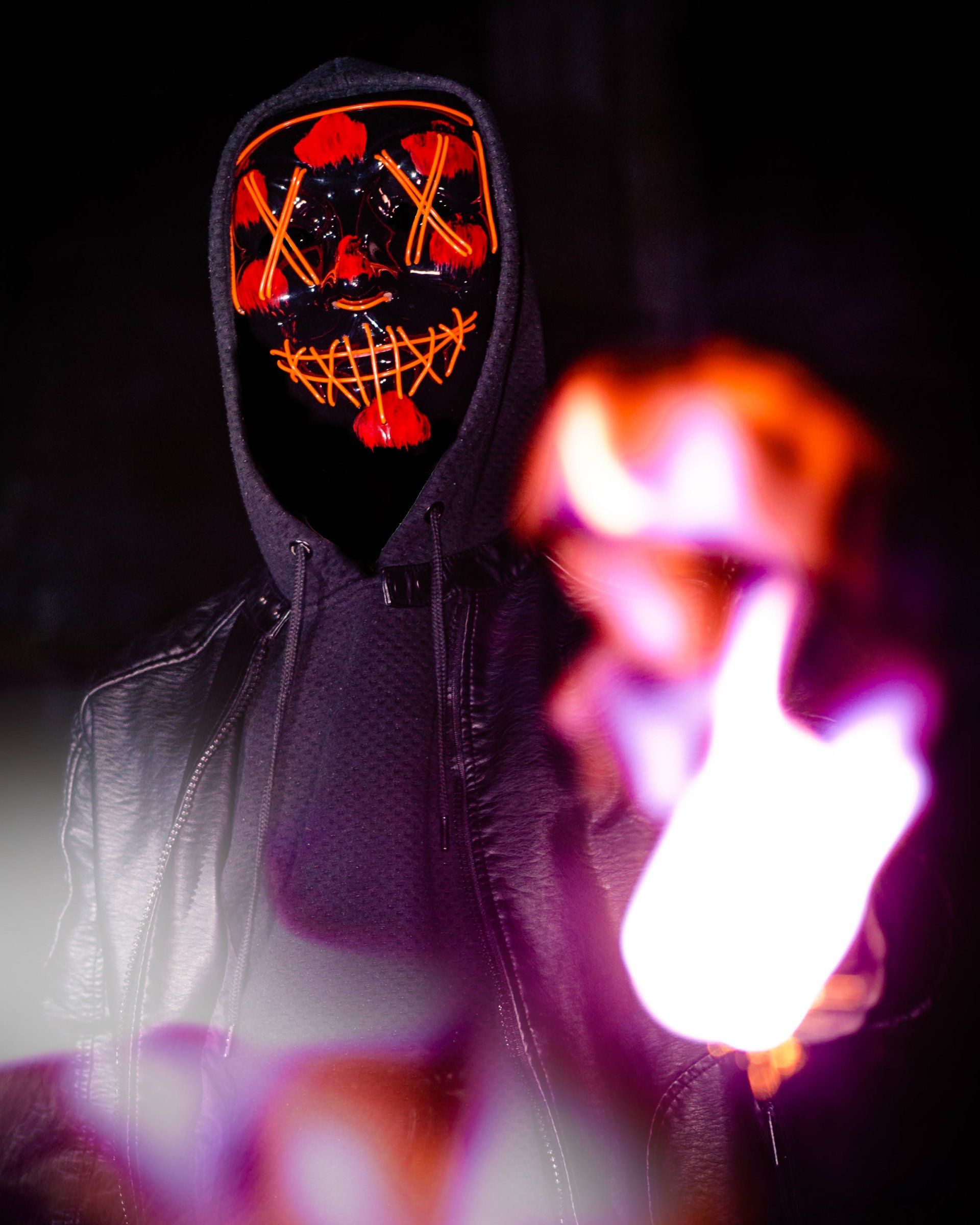 Kreatives Rauchportrait einer Person mit leuchtender LED-Maske in dunkler Atmosphäre