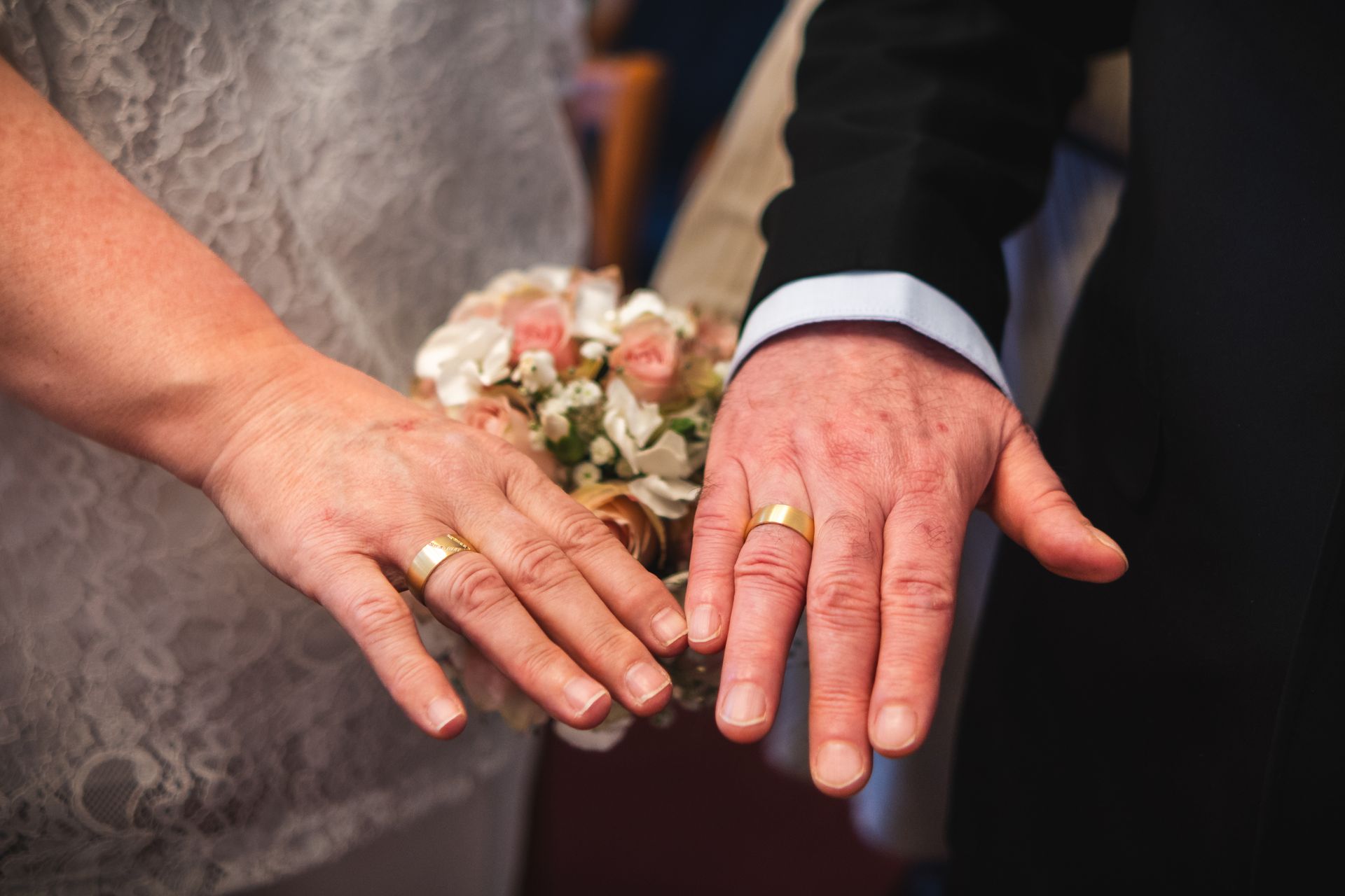 Detailaufnahme von Braut- und Bräutigamhänden mit Eheringen während der Hochzeit