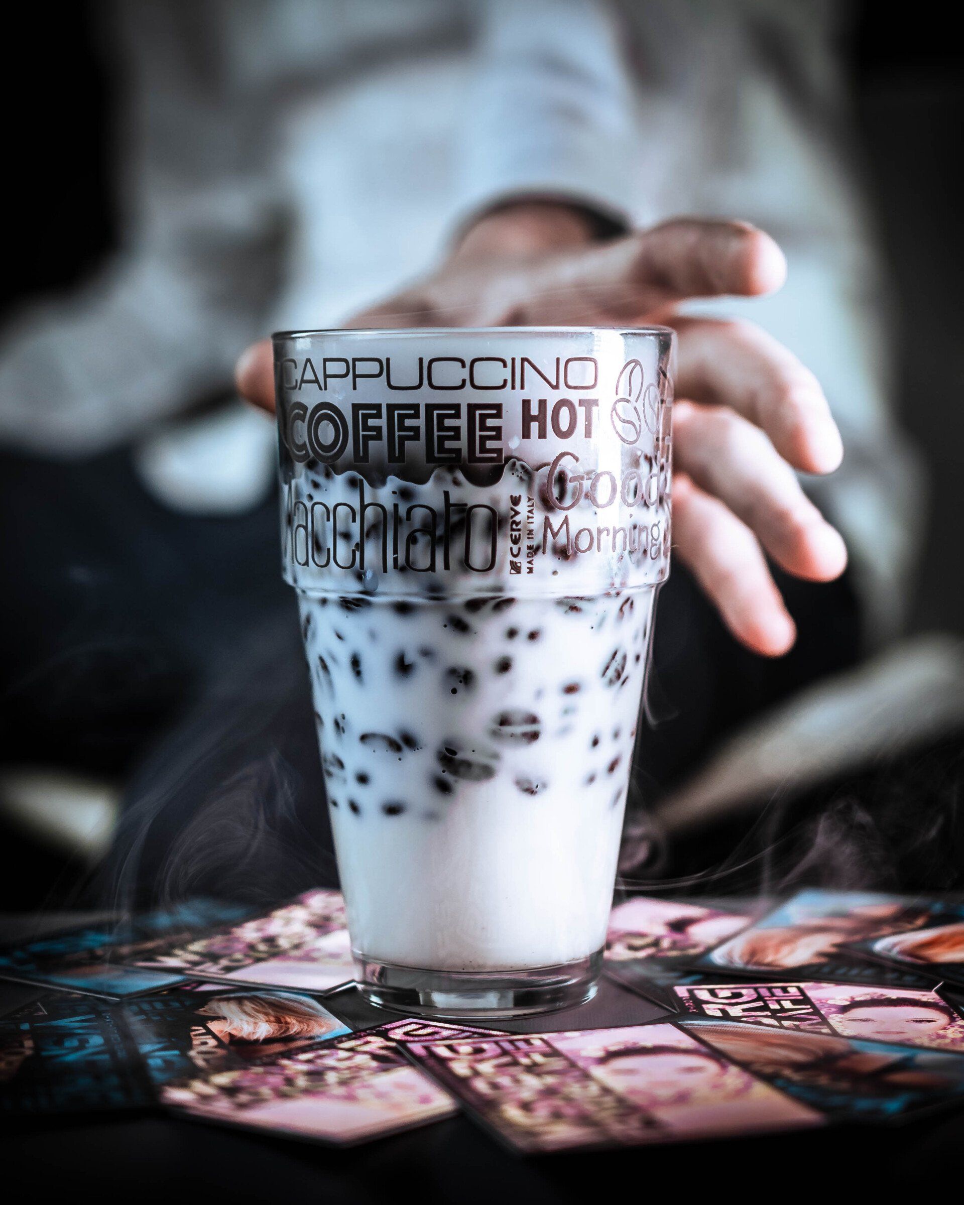 Milchgetränk im Schriftglas mit Bubble Tea & Manga-Karten – kreative Lifestyle-Fotografie mit Dampf & Hand im Hintergrund
