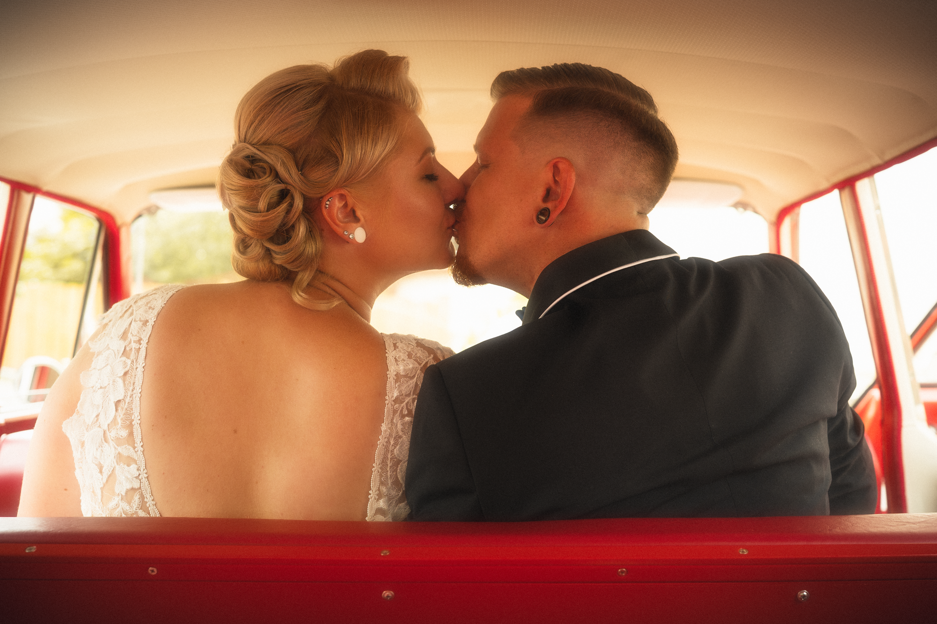 Intimer Hochzeitsmoment, Brautpaar küsst sich auf der Rückbank eines Oldtimers