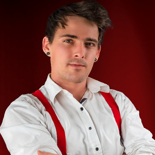 Portrait von Kevin Wesenberg – Hochzeitsfotograf aus Leipzig mit weißen Hemd, roten Hosenträgern und tätowiertem Unterarm vor rotem Hintergrund