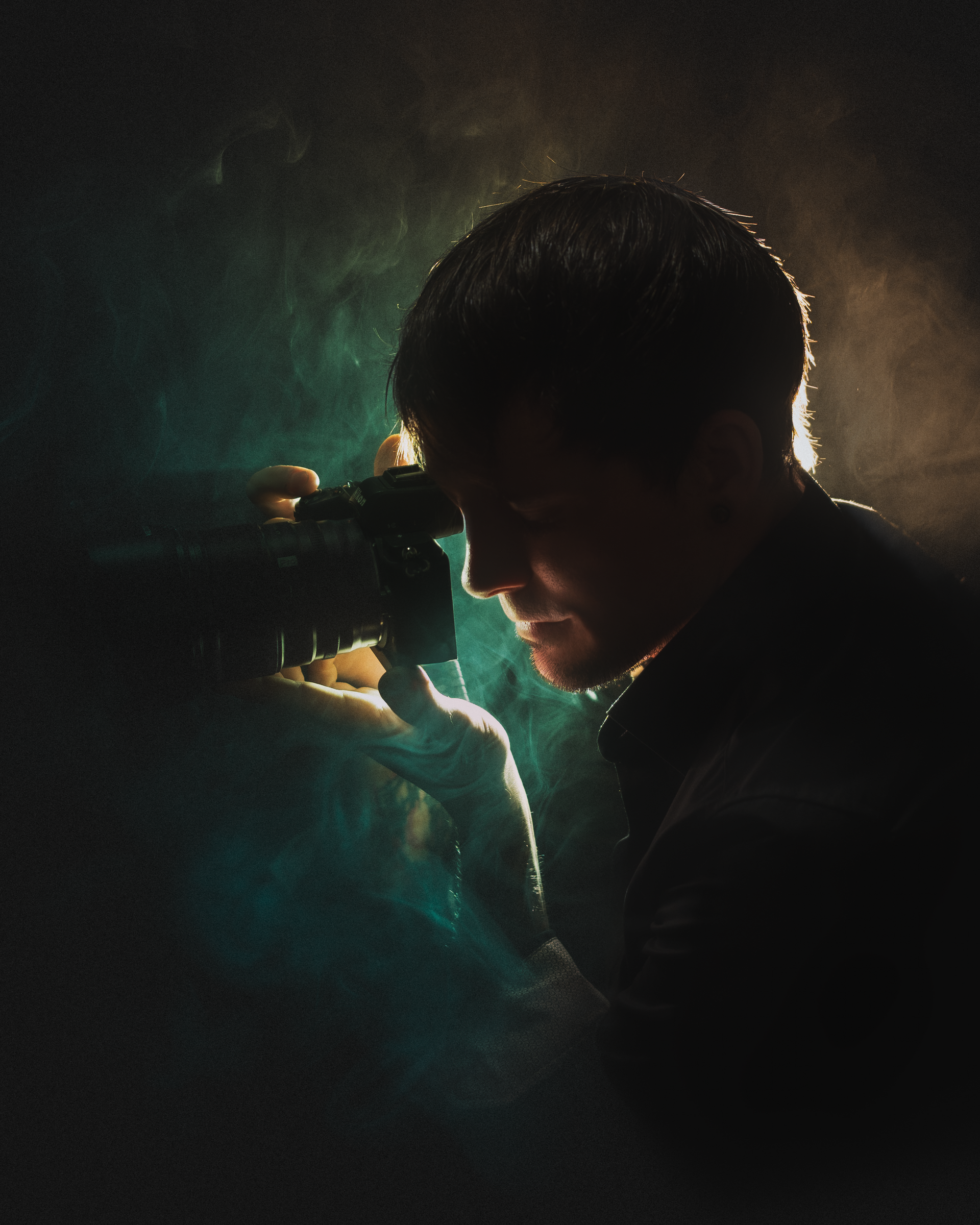 Künstlerisches Portrait des Fotografen im Gegenlicht mit Rauch und dunkler Atmosphäre