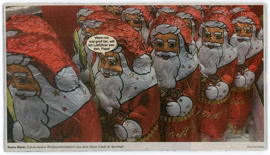 Postkarte mit dicht gereihten Schokoladenweihnachtsmännern und Sprechblase über Lokführer und den Papa.