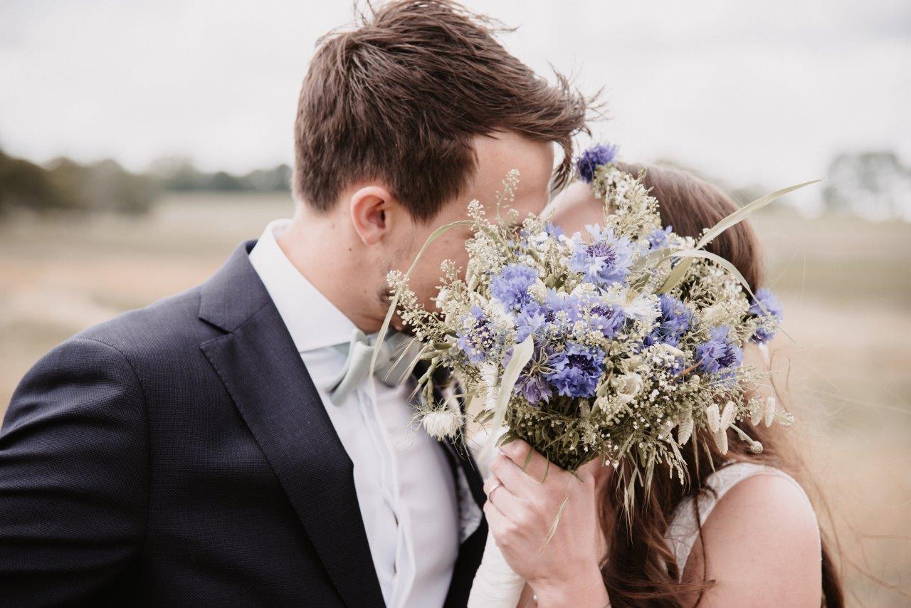 <img src=”Hochzeitsfotograf-Kiel-Brautpaar-versteckt-hinter-Blumenstrauß.jpg” alt=”Brautpaar küsst sich versteckt hinter einem Blumenstrauß”>