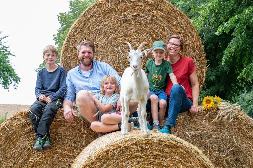 Familie sitzt auf Rundballen
