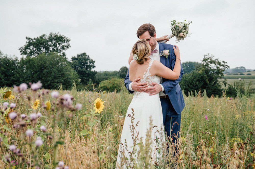 Brautpaar auf Blumenwiese, umarmt sich