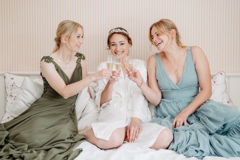 getting ready, Braut mit Trauzeugen sitzend auf dem bett und prosten sich zu