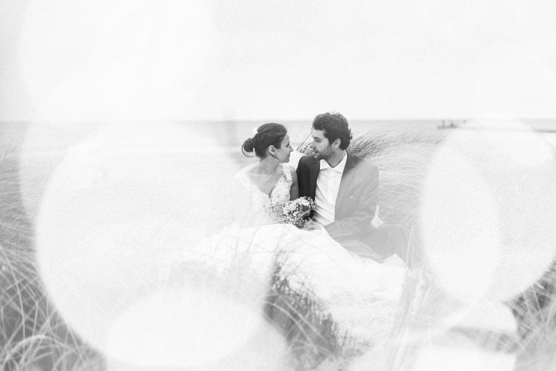 schwarz weiß Foto eines Brautpaares dass in den Dünen sitzt