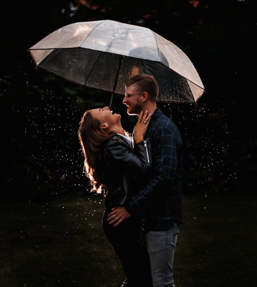 Paar lachend unter einem Regenschirm im Regen