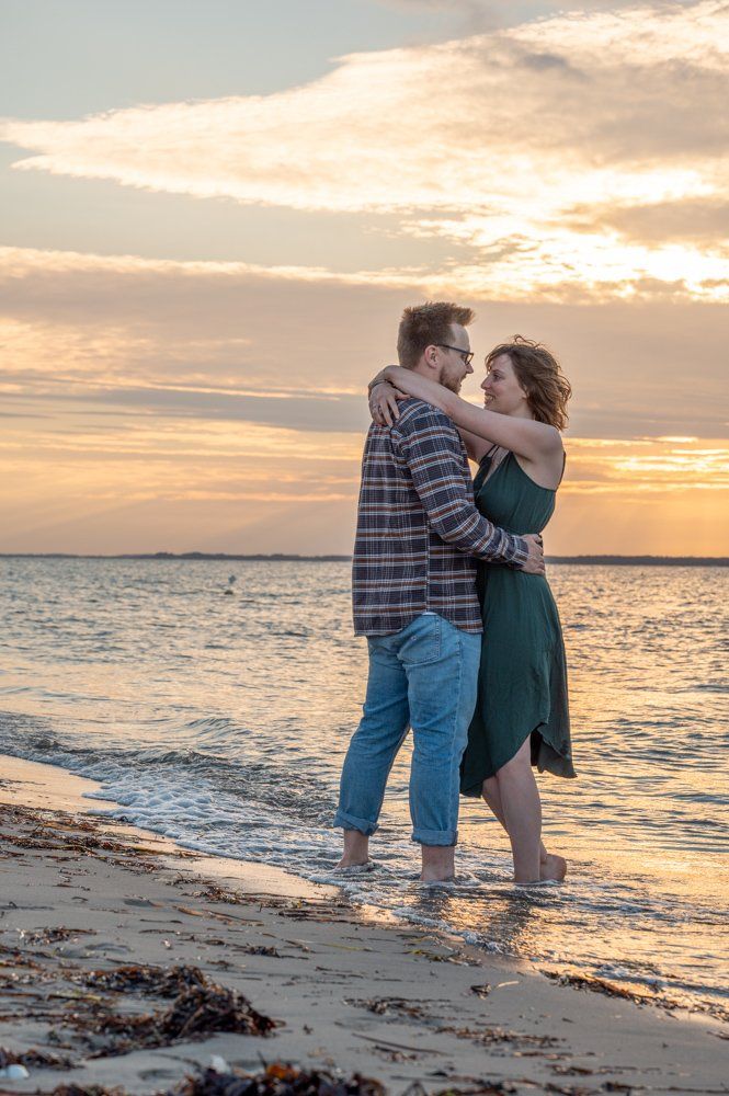 Strandportrait, Paar steht im Sonnenuntergang im flachen Wasser am Strand