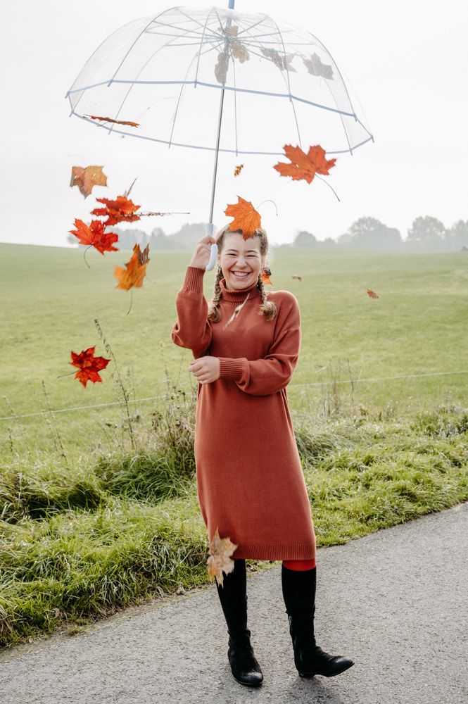 Mädchen mit Regenschirm aus dem Blätter fallen