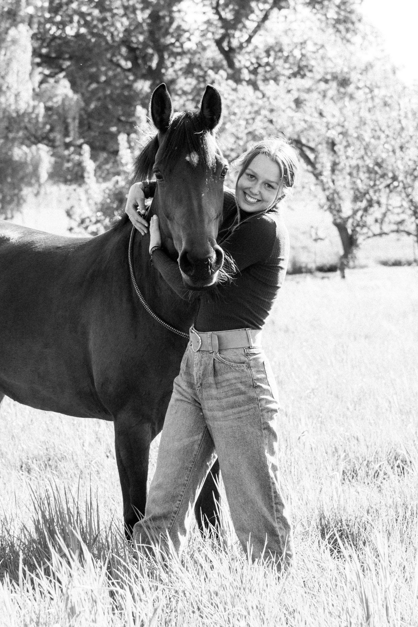 Mädchen umarmt ihr Pferd auf einer Wiese