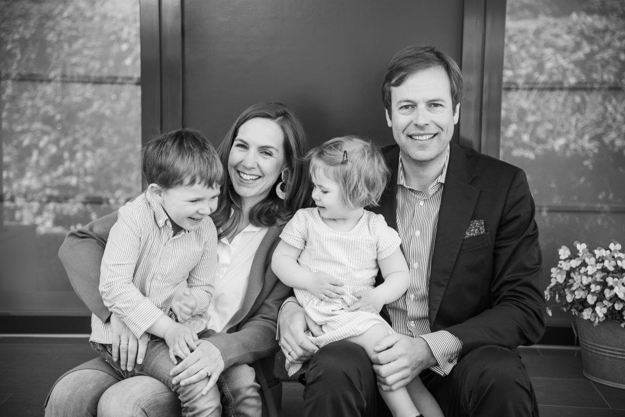 Familie mit 2 Kindern sitzend vor ihrer Haustür