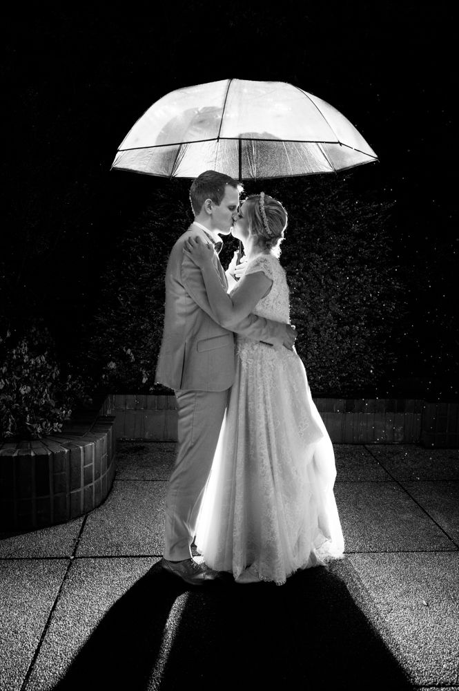 Brautpaar im Dunkeln unter Regenschirm im Regen