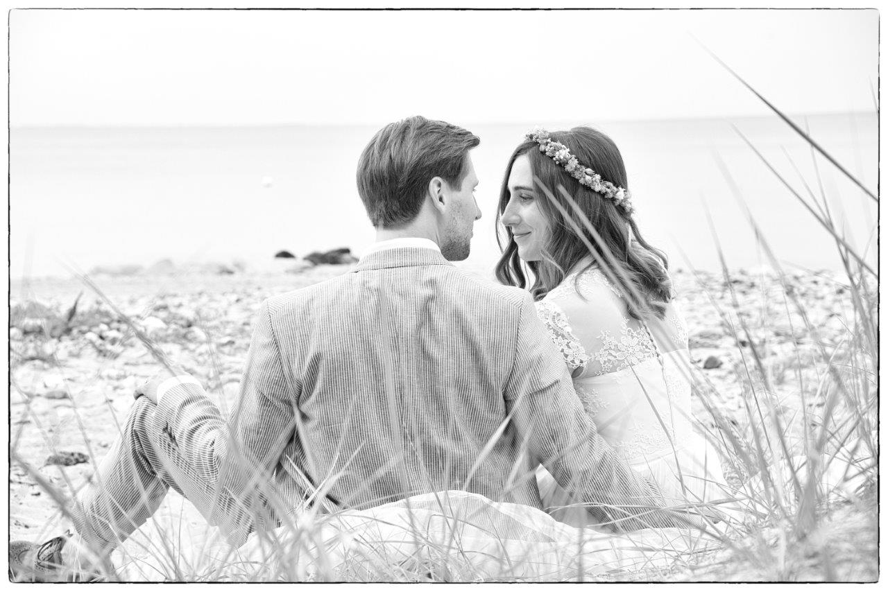 <img src=”Hochzeitsfotograf-Kiel-Brautpaar-sitzend-in-den-Dünen-von-hinten.jpg” alt=”Brautpaar sitzt in den Dünen von hinten gesehen und schaut sich an”>