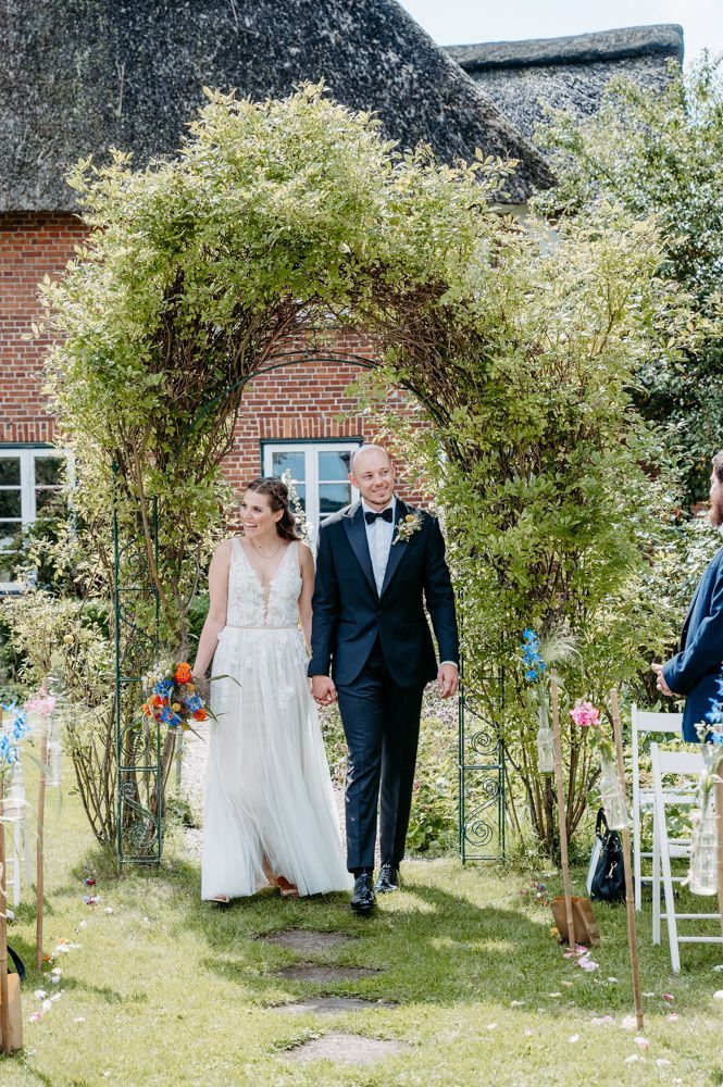 Paar geht lachen Hand in Hand durch einen Garten