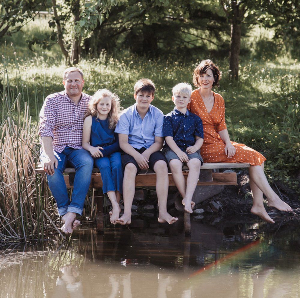 Familienfoto von Eltern mit 3 Kindern auf einem Steg an einem See