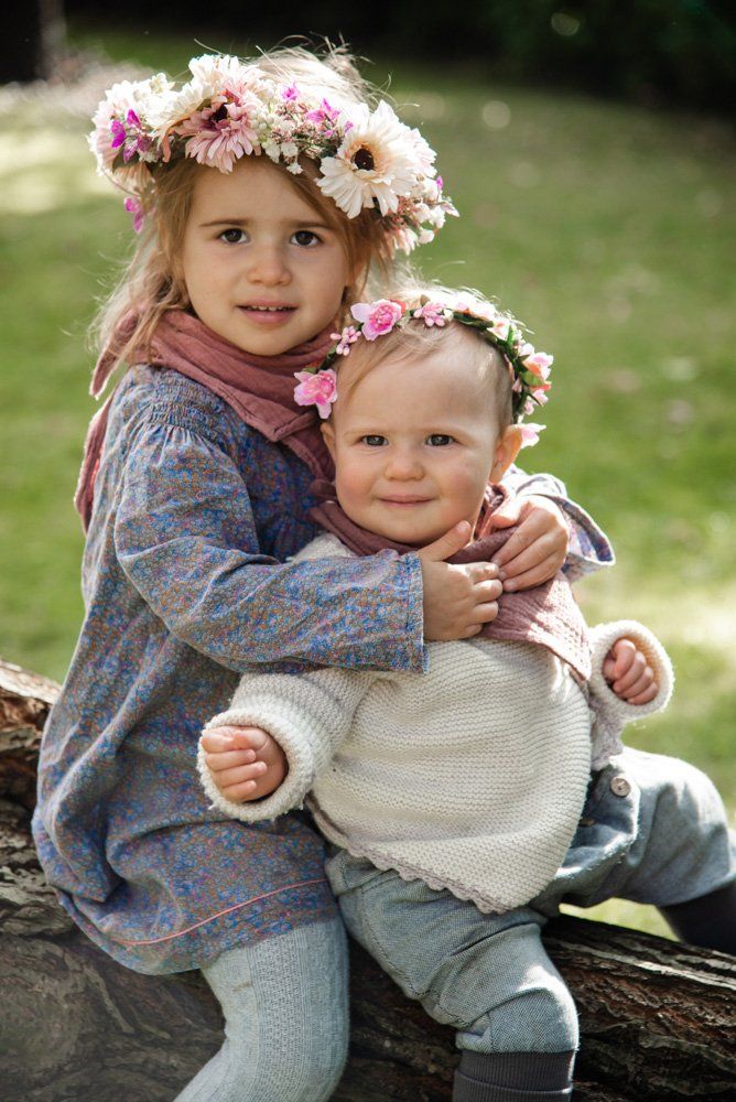 Portrait von 2 Geschwistern, die kleine sitzt zwischen den Beinen der großen