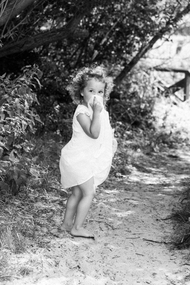 Mädchen läuft Weg entlang und versteckt sich hinter ihrem Kleid