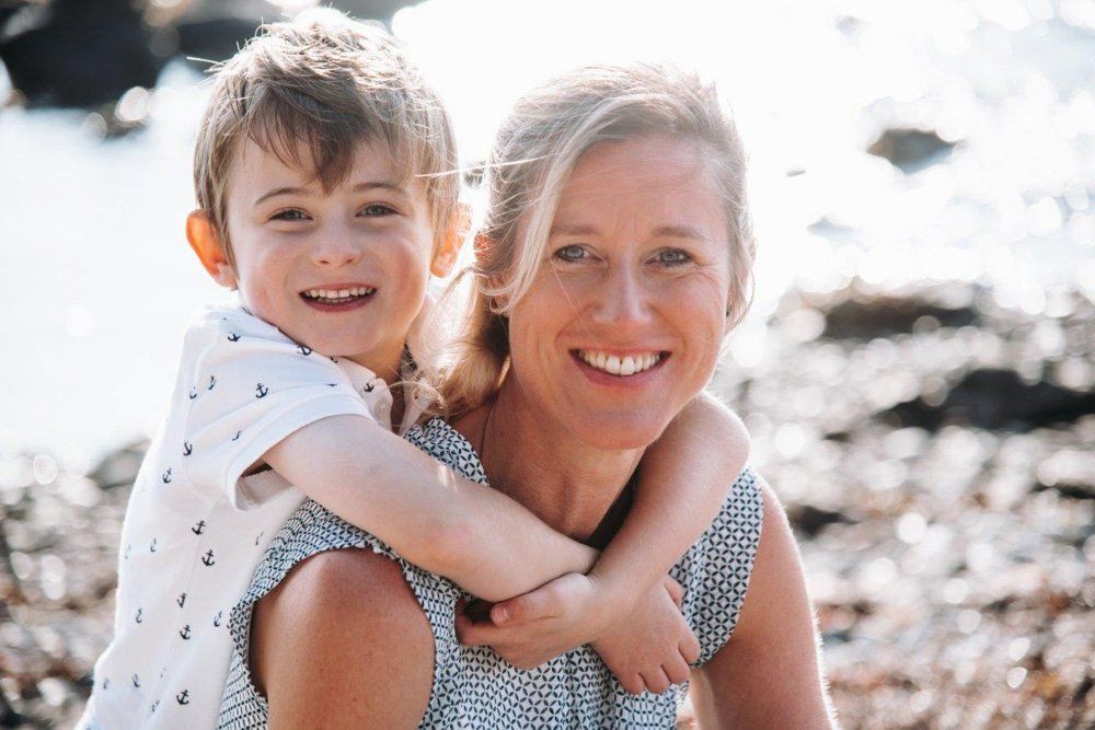 Mutter und Sohn am Strand, Sohn umarmt Mutter von hinten