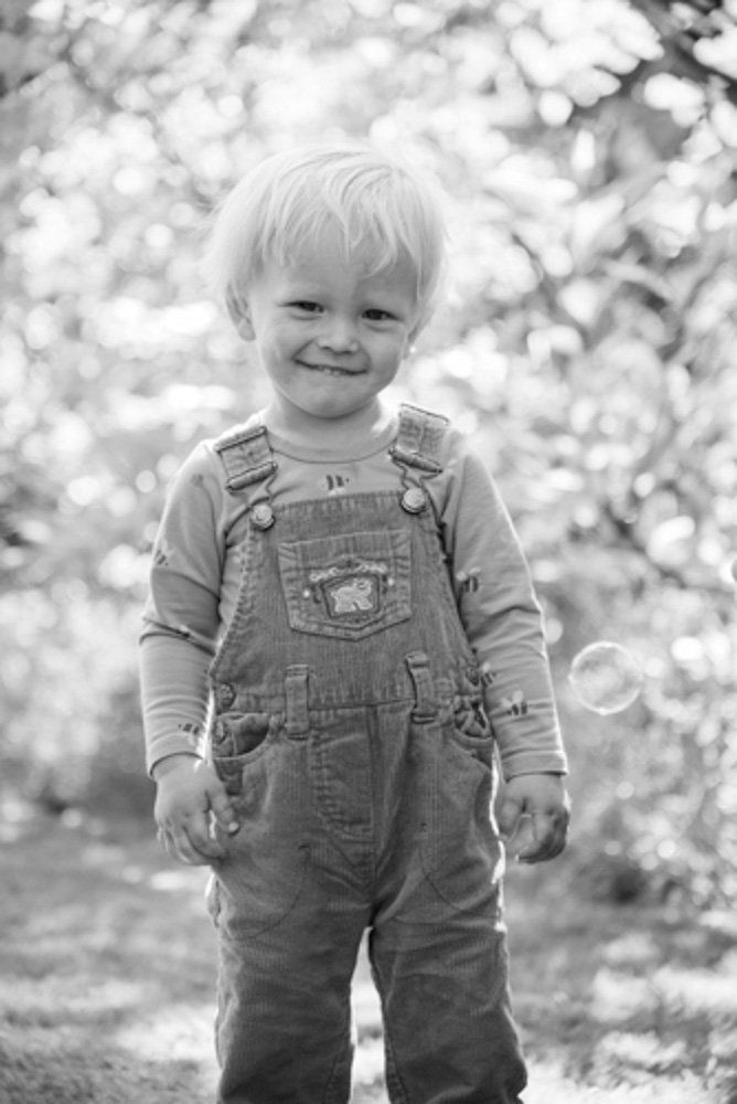 kleiner Junge mit Latzhose in hohem Gras