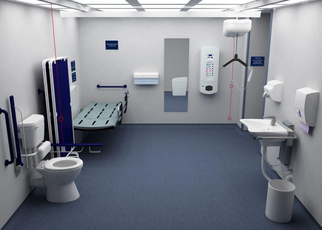 a clinical looking changing places toilet showing a sink on the right hand side, toilet on the left hand side and changing bed against the back wall