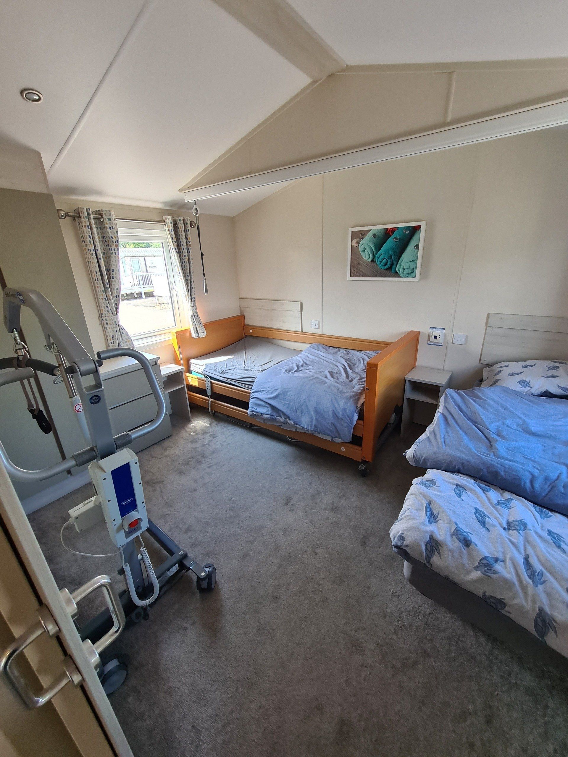 an image of the profiling bedroom in the sign along with us foundation caravan and showing the electric hoist, with a second single bed on the left hand side