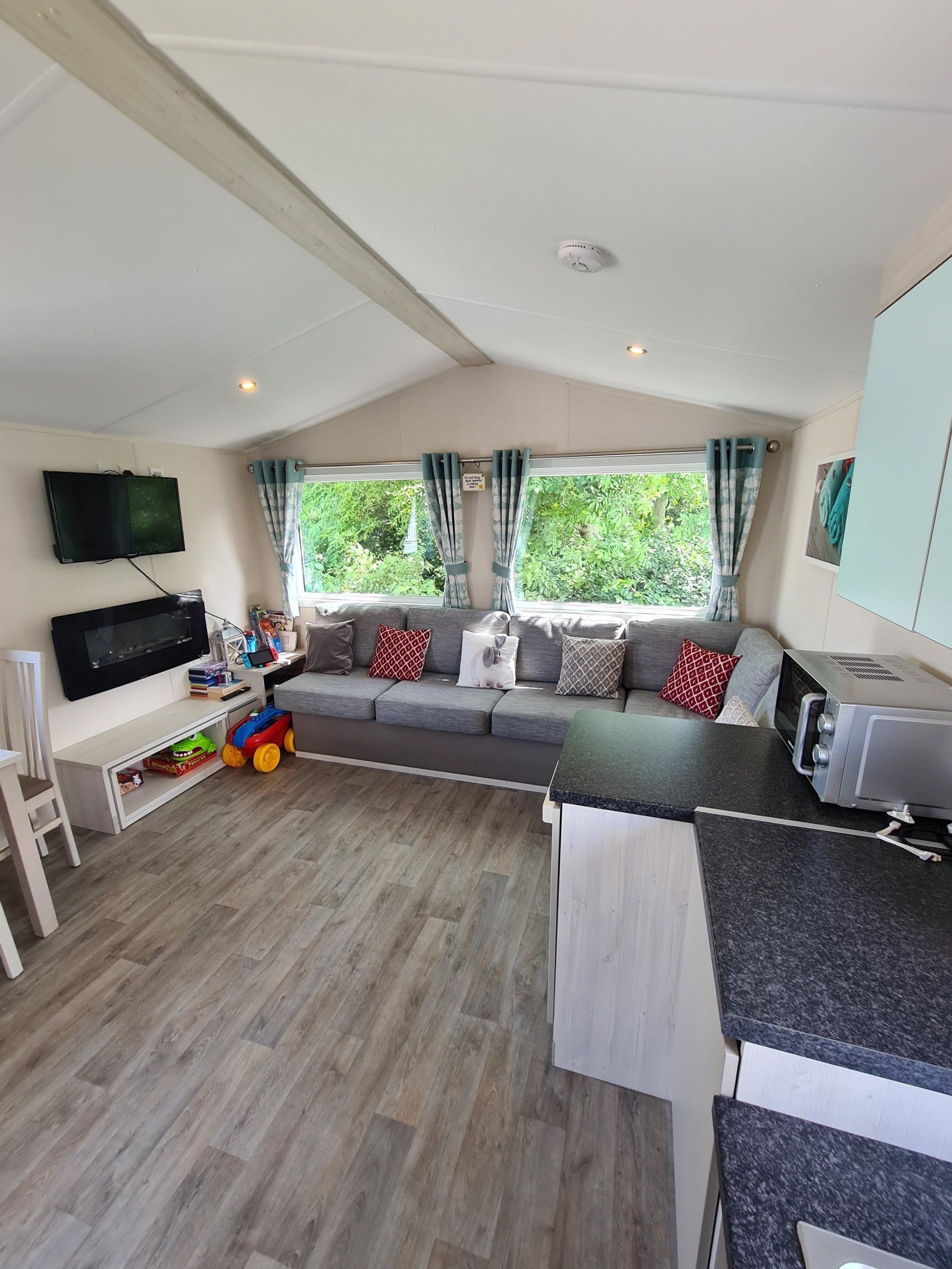 a view of the living area from the lowered kitchen showing the corner sofa which turns into a sofa bed and television on the wall
