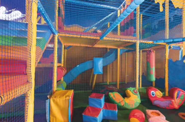 a picture of a colourful soft play area at haven showing mesh, slides and cushioned play items