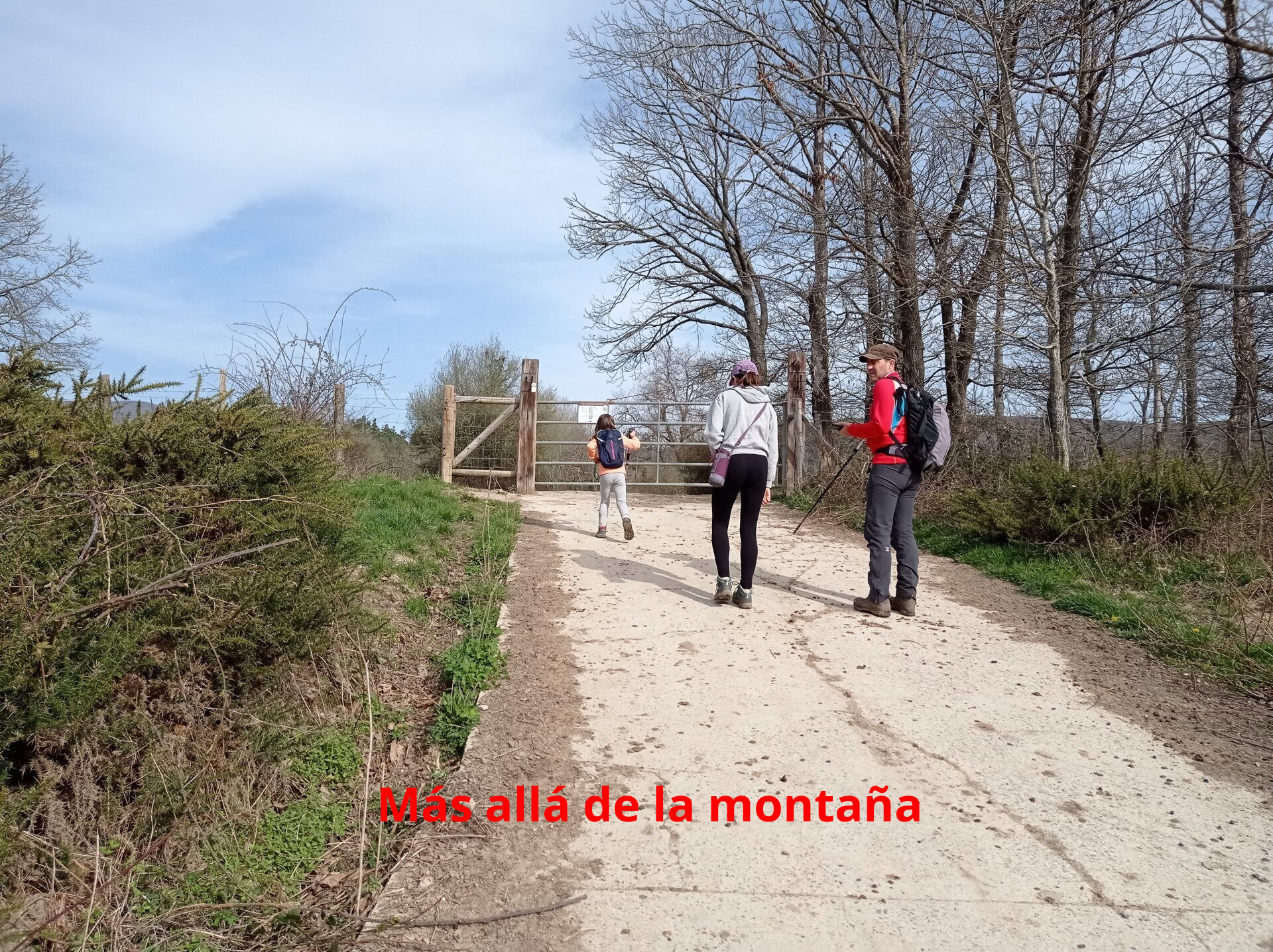 A la izquierda, hay una barrera metálica que da paso a un camino.
