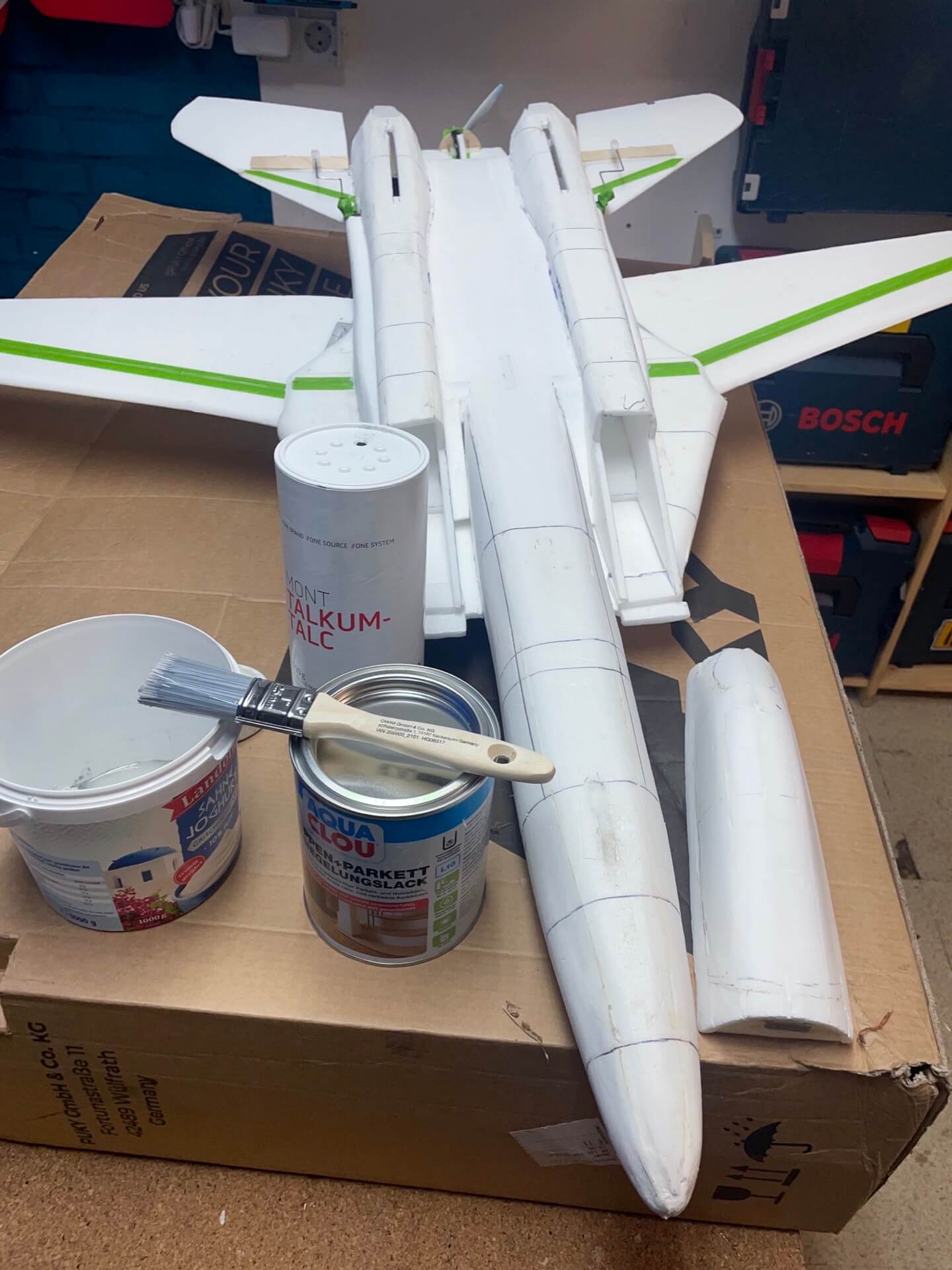 Verwende alte Kartonagen zum Schutz. Hier siehst Du die Sauerei. Schutz mit Pappe für die Oberfläche der Lackierung der Depronjets.