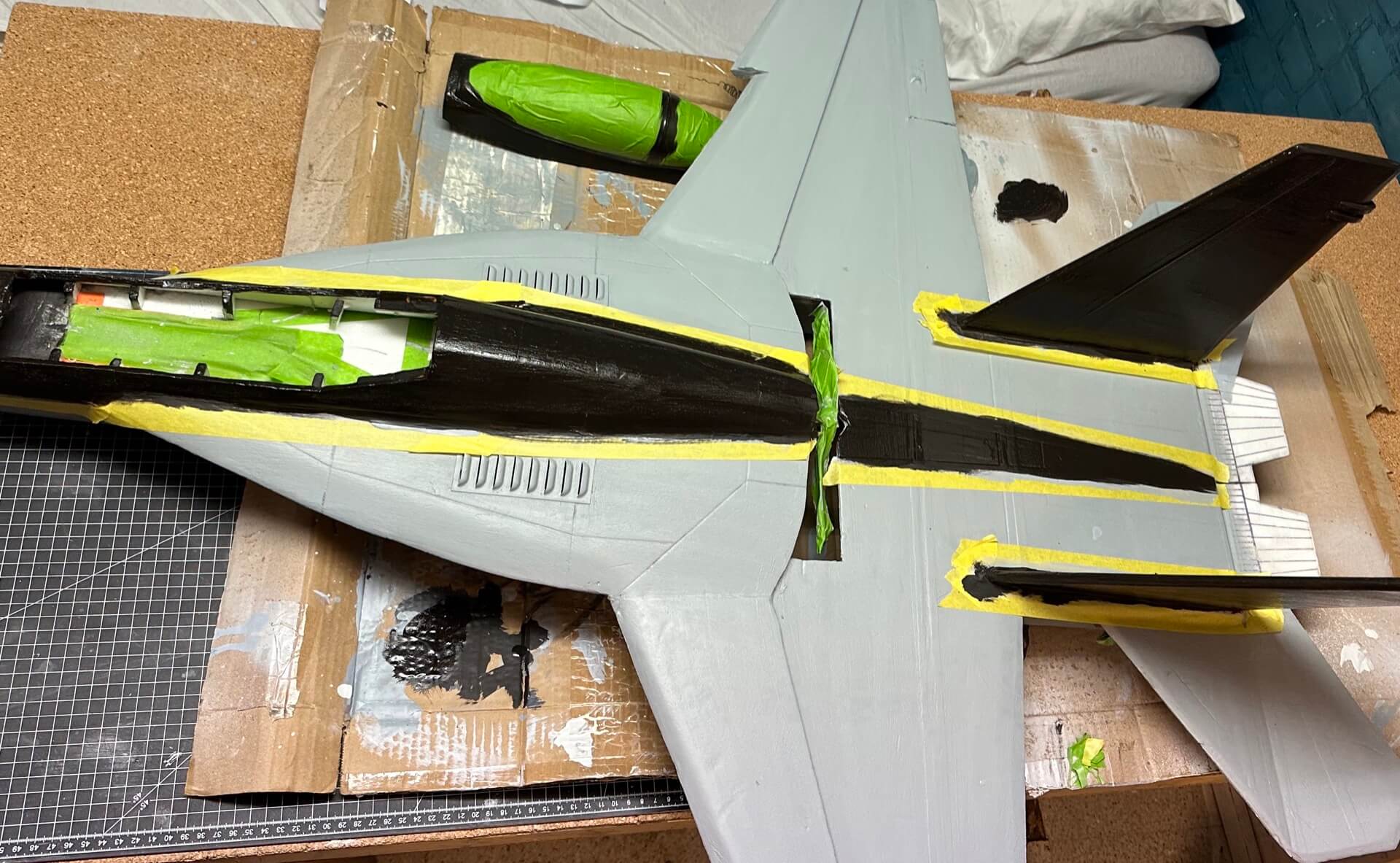 Fertig lackierter Rumpf der F-18. Oben liegt noch die Kabinenhaube, die ich ebenfalls lackiert habe. Da meine Pinseltechnik und meine ruhige Hand nicht ausreichten für gerade saubere Linien, habe ich den transparenten Bereich kurzerhand abgeklebt. Dann muss man nicht so aufpassen. Fertig lackierter Rumpfrücken der F-18.